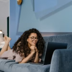 a young woman video calling with a laptop on a couch